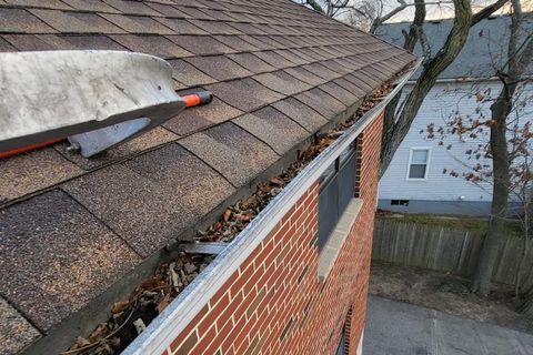 Technician cleaning a gutter from a ladder